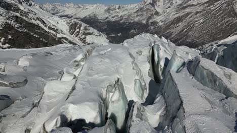 Aerial-push-in:-snowy-mountain-facade-in-the-alps,-rocks-and-snowy-peaks