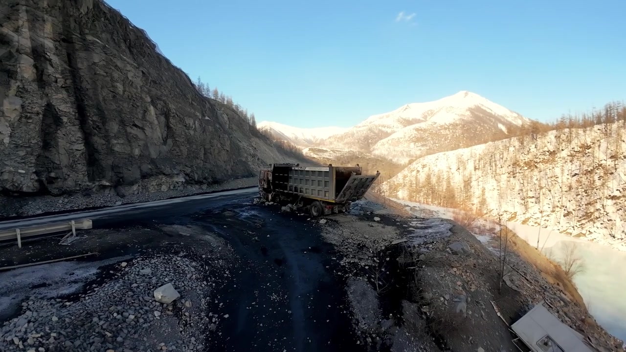 Un grosso dumper percorre una tortuosa strada di montagna. Durante il tragitto sono visibili viste panoramiche del paesaggio.