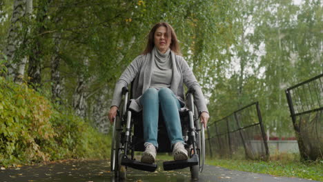 mujer en silla de ruedas camina en el parque del sanatorio durante la recuperación