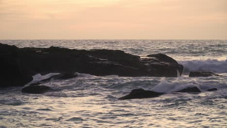 Mar-Agitado-Con-Olas-Rompiendo-Contra-Las-Rocas-En-El-Mar,-En-Una-Puesta-De-Sol