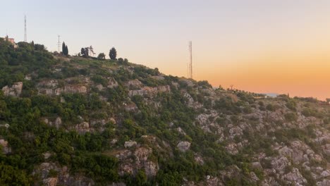 electricity pylons and communication towers on rocky mountain in kaslik, keserwan district, lebanon with golden hour sunset by the sea revealed