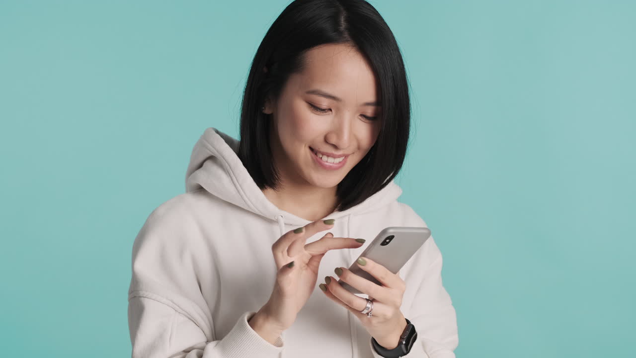 Asian woman taking selfie on smartphone.