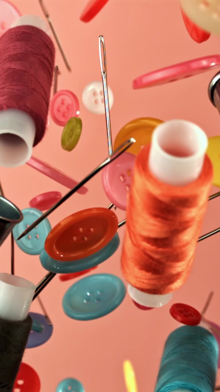Colorful Sewing Supplies Floating in Slow Motion on Pink Background