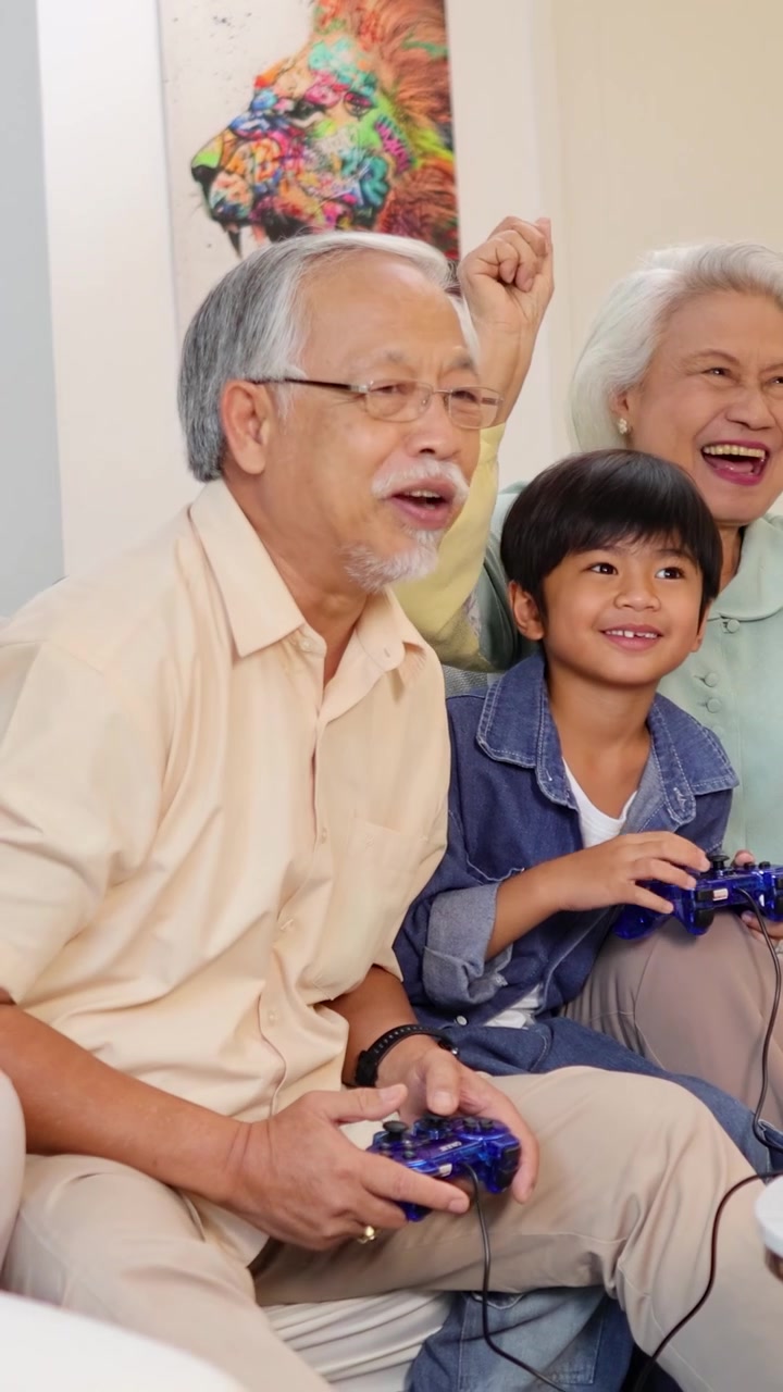 明るくモダンなリビングルームで、多世代のアジア人家族が楽しそうに一緒にビデオゲームをしている