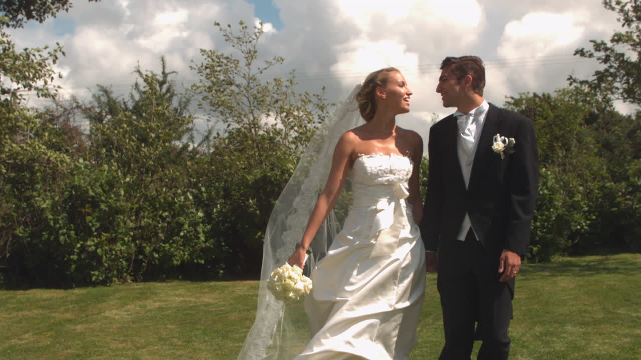 una pareja de recién casados caminando y besándose.