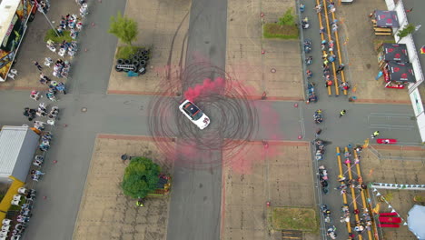 aerial view of sports car drifting in circle with red smoke and tire tracks