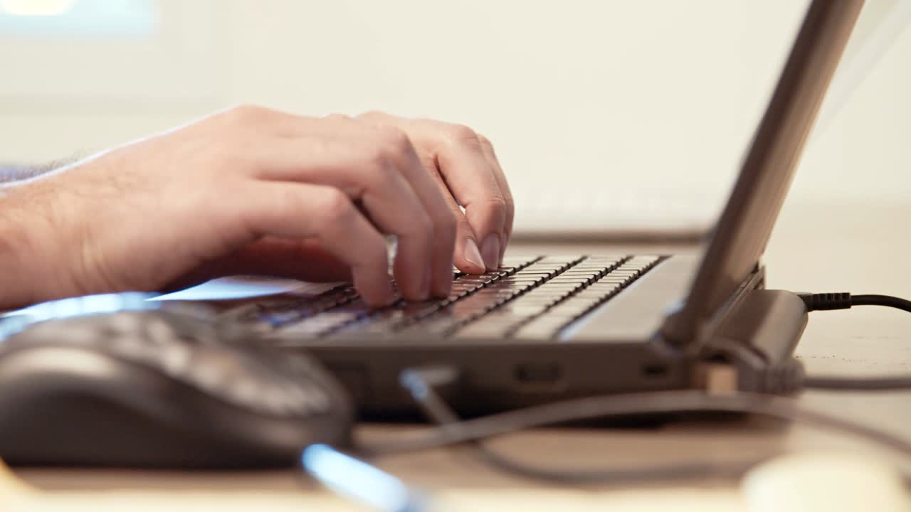 manos del hombre escribiendo en un teclado de computadora portátil