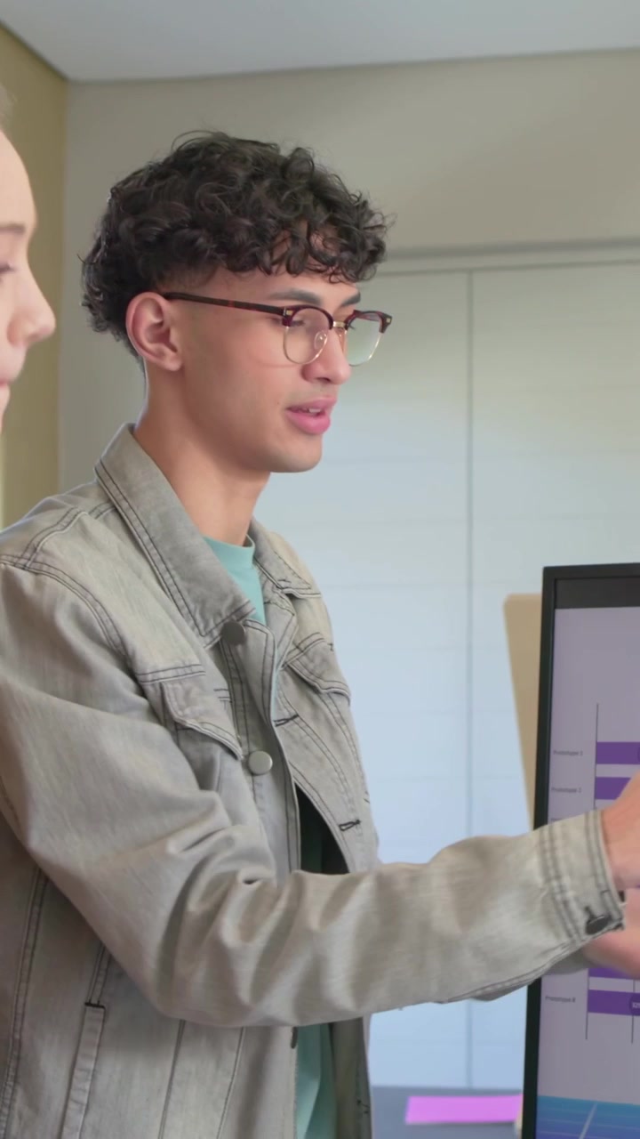Pointing woman in blazer leading man with glasses explaining purple chart in meeting, copy space