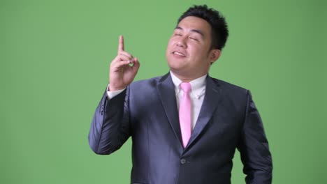 초록색 배경에 젊은 잘생긴 과체중 아시아 사업가