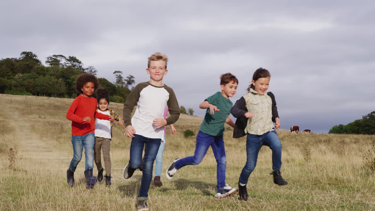 Front View Of Group Of Children On Outdoor Activity Camping Trip Running Down Hill