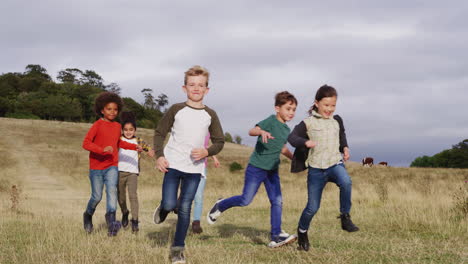 front view of group of children on outdoor activity camping trip running down hill