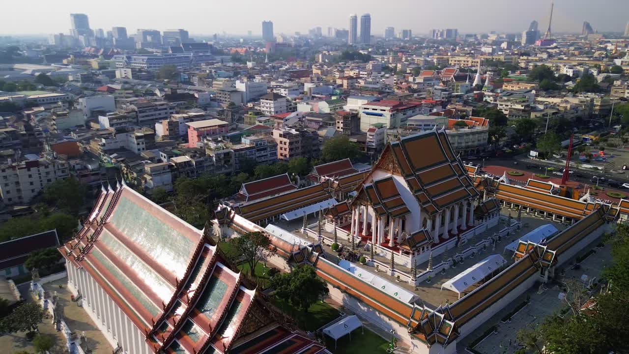 Aerial orbit reveal Wat Suthat, Bangkok, temple complex, red roofs, and intricate architectural details