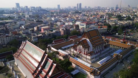 aerial orbit reveal wat suthat, bangkok, temple complex, red roofs, and intricate architectural details