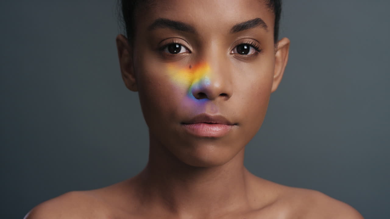 retrato multicolor hermosa mujer afroamericana con luz colorida que se refleja en una piel suave y saludable atractivo concepto de cuidado de la piel femenino en fondo gris