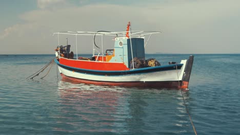 traditional carvel built greek fishing boat moored at sea ramped slow mo, pan up