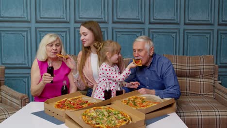 familia feliz teniendo una fiesta de almuerzo, alimentándose el uno al otro con pizza, riendo disfrutando de la comida juntos en casa