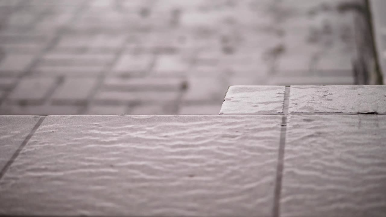 primer plano, hay una fuerte lluvia, una lluvia, grandes gotas pesadas gotean sobre las baldosas de la calle. gota de lluvia en la textura del suelo húmedo, fuertes gotas de lluvia sobre el asfalto. charcos de agua durante la fuerte lluvia