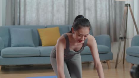 스포츠 옷을 입은 젊은 아시아 트레이너 여성이 카메라에 대화하고 집에서 가르치는 운동을 녹음하는 동안 균형 잡는 테이블 포즈에서 요가를합니다.