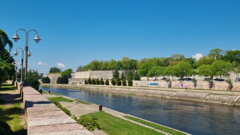 wide view of the nišava river and the riverside promenade in niš, serbia, on a sunny spring day, with clear blue skies and a relaxed atmosphere along the water