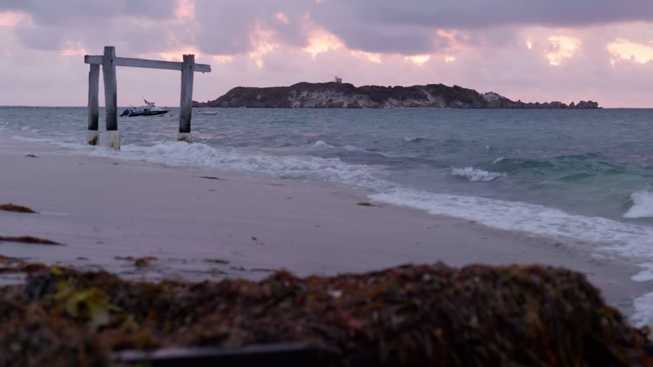 Hamelin Island at sunset, with waves crashing against the shore, creating a serene and breathtaking coastal scene as the sun dips below the horizon.