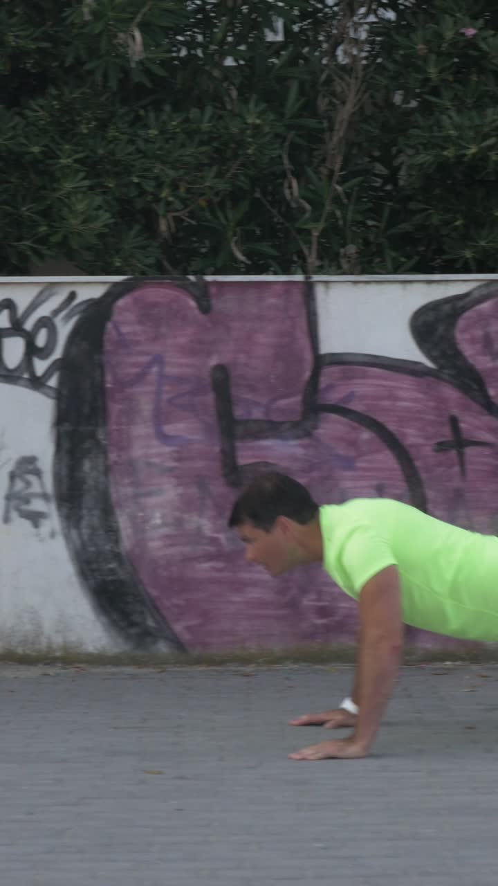 Donna che salta la corda e uomo che fa flessioni all'aperto davanti a un muro graffitato