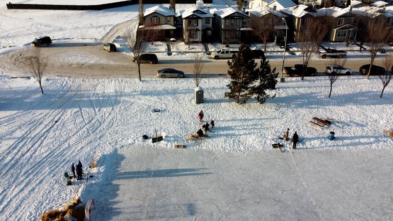 겨울 공중 상승 주거 지역 사회 인공 아이스 링크 사람들이 스케이트 하키를 연습하고 지역 사회 공원 밖으로 스케이트를 배우는 사람들 피크닉 테이블 화재 구덩이 건초 더미 1-3에서 의사 소통