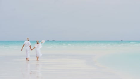 senior caucasian couple walking together on island beach