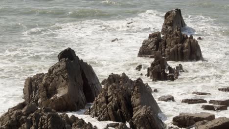 medio disparo de olas chocando contra rocas dentadas en el mar de cornualles en el muelle de hartland, stoke, hartland, bideford