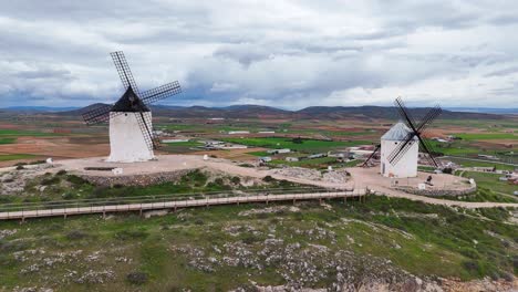 slow-motion drone view of two consuegra windmills on cloudy day