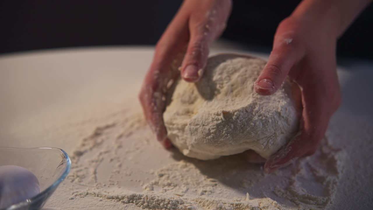 Primo piano di mani che impastano l'impasto su un tavolo infarinato