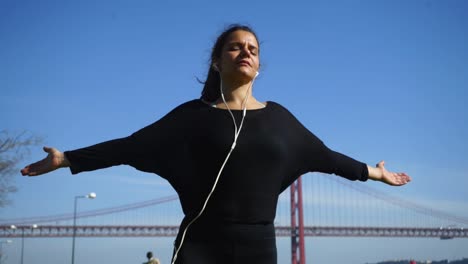 Sporty-girl-in-earphones-meditating-against-blue-sky