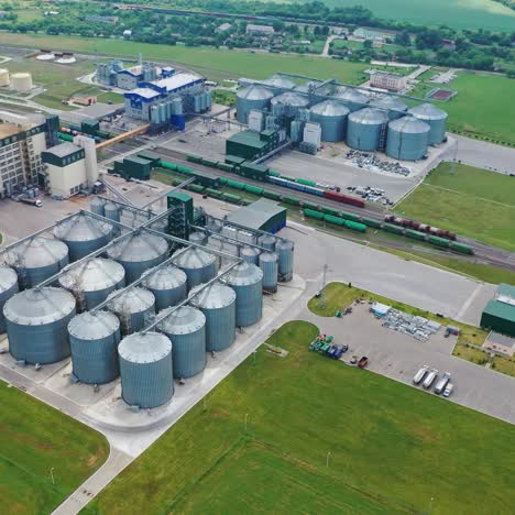 agricultural land and grain silo. steel grain silos elevators storage among green nature. agriculture industry. aerial video.