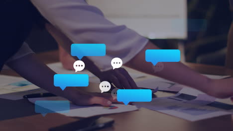 Animation of message icons against mid section of colleagues discussing over documents at office
