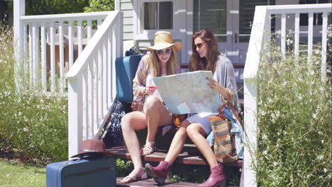 hermosos amigos planeando su viaje por carretera con maleta y mapa