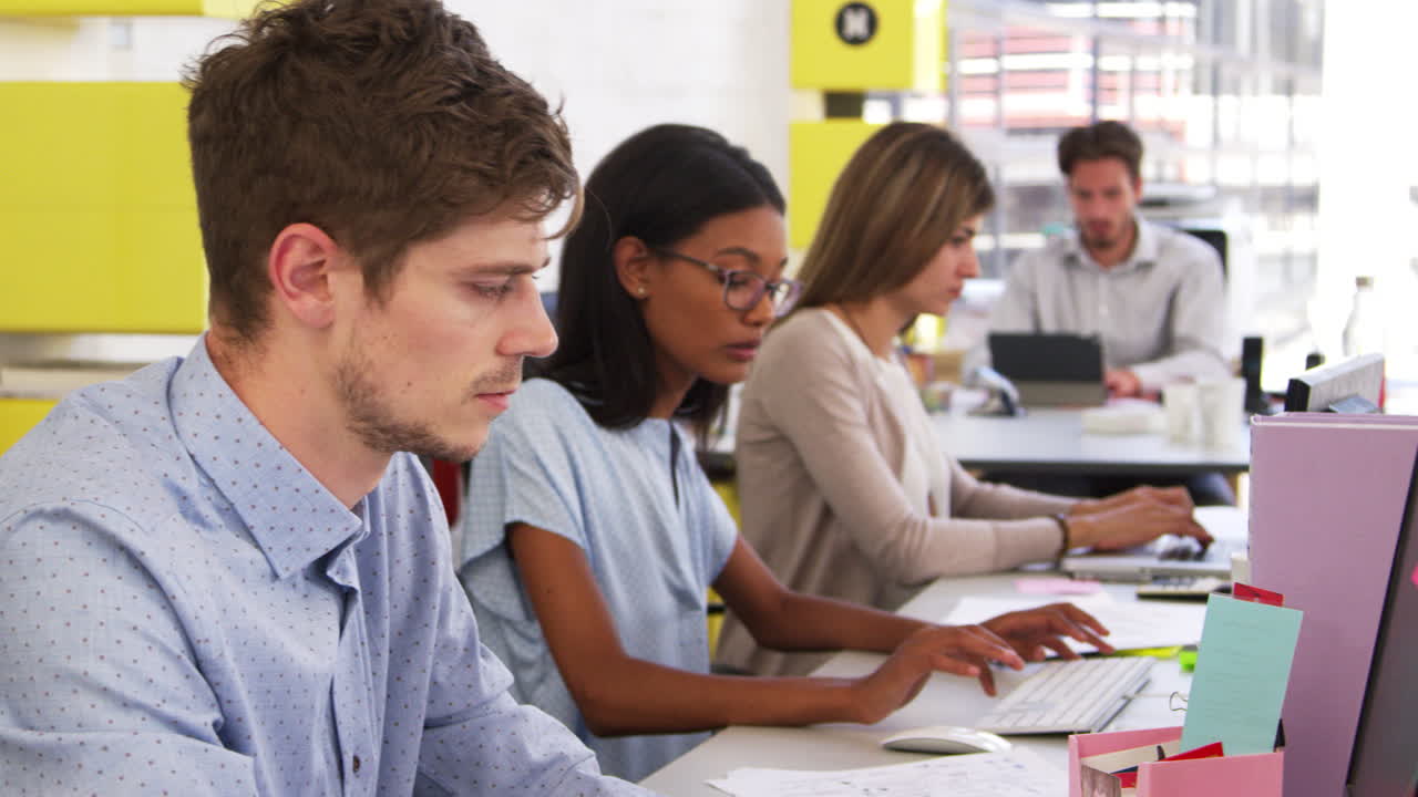 Young team working in a busy open plan office, panning shot
