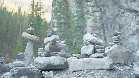 a collection of several man made rock inuksuit statues in a dried up river bed in the bright sun