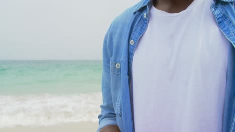 vista lateral de un hombre afroamericano usando teléfono móvil en la playa 4k