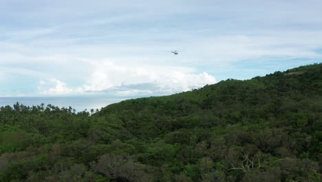 helicóptero con carga colgando del cable que vuela hacia el helipuerto en una isla remota