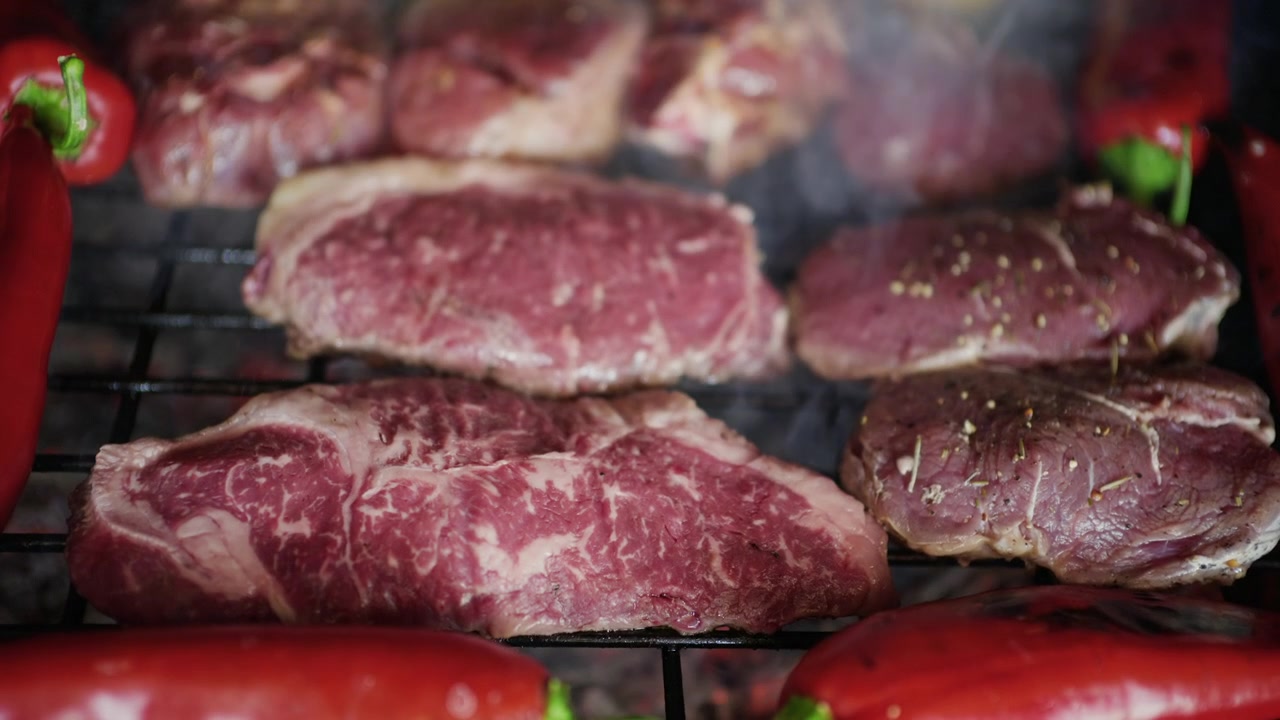 Carne alla griglia con segni di scottatura visibili, mentre viene girata durante la cottura su braci ardenti, accompagnata da verdure