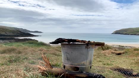 time lapse of wood burning in a camp bucket barbecue grill with the ocean as background