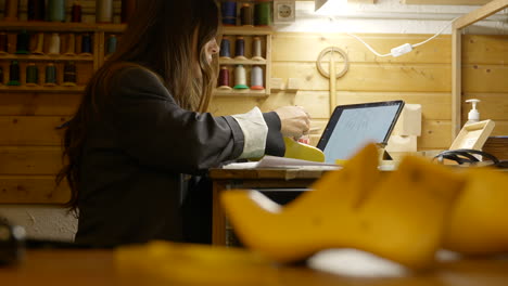 zapatero femenino dibujando un patrón único en el último zapato con tableta digital en el banco de trabajo