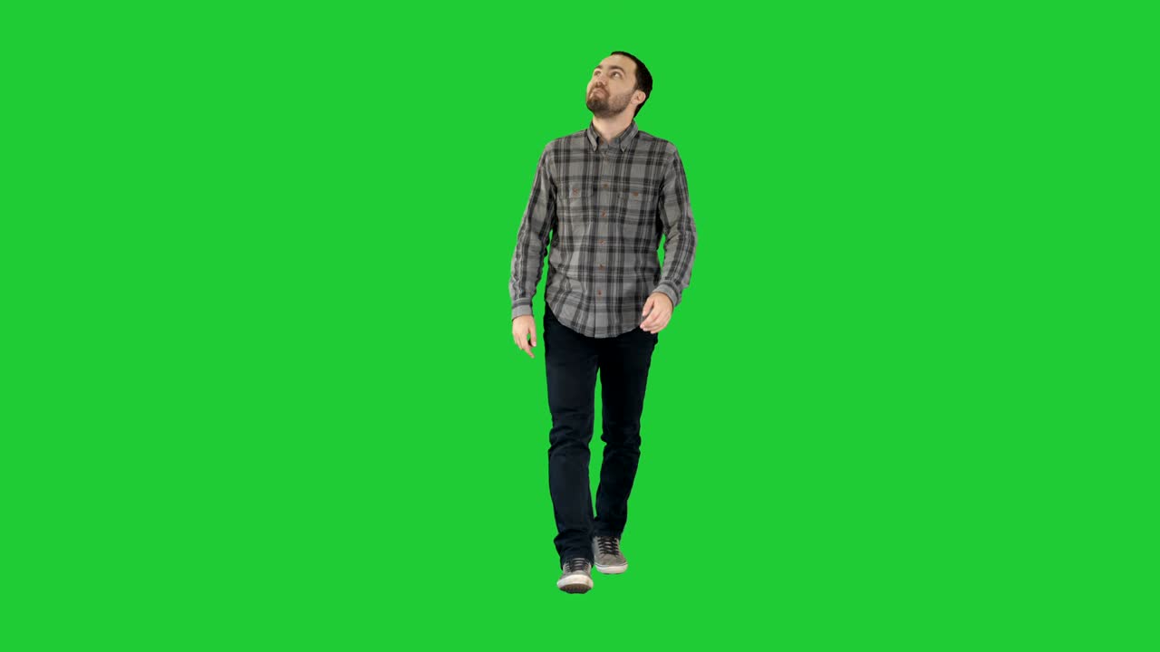 Giovane uomo che cammina guardando in alto affascinato su uno schermo verde, Chroma Key.