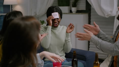 multiracial friends playing funny game using sticky notes having fun together