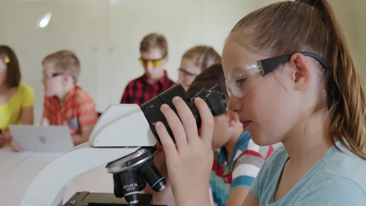 niña con gafas usando el microscopio