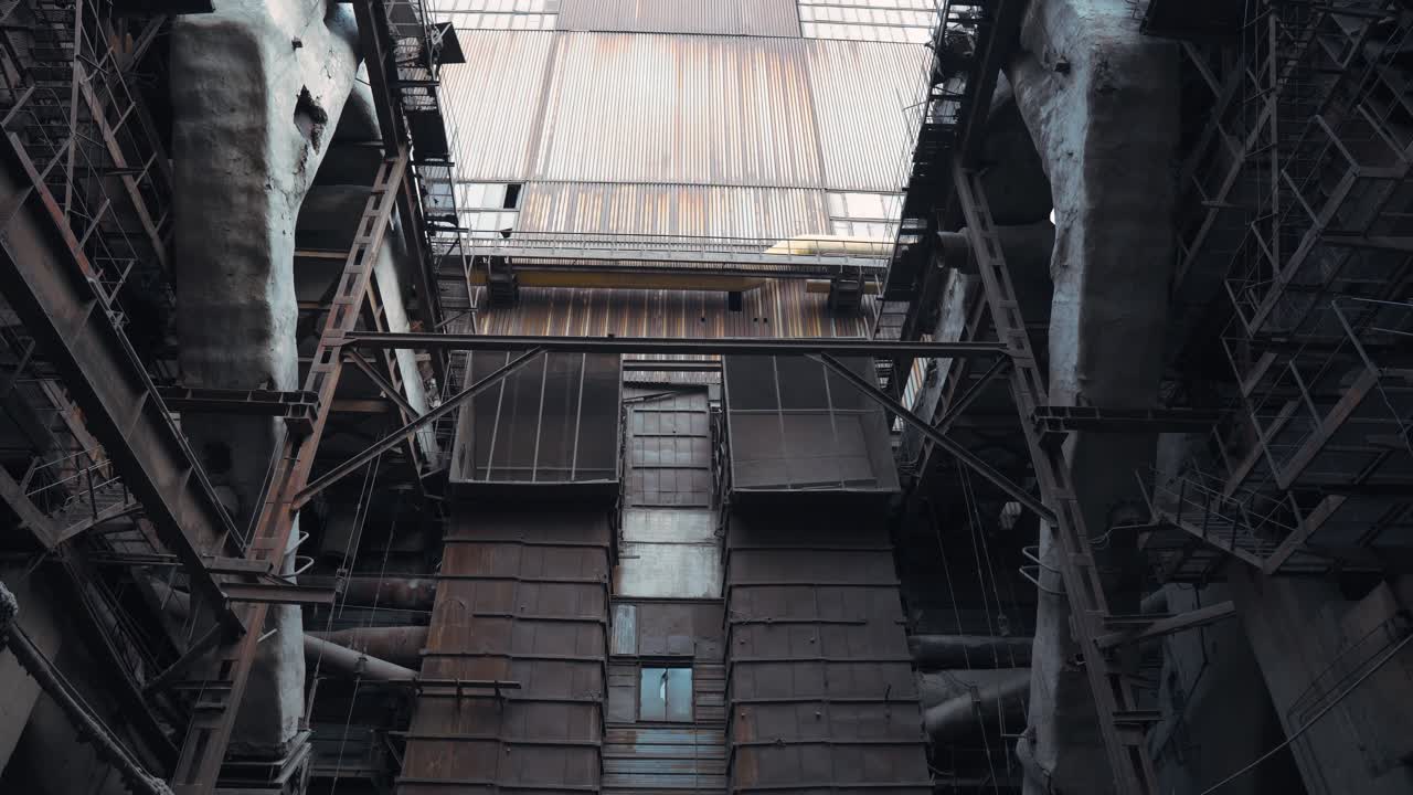 Ruined and abandoned old rusty tall industrial structures at an old coal-fired power plant. Iron stairs. Polluted environment