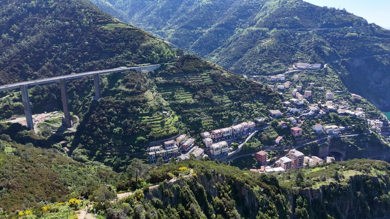 Drone footage of a small village on the coast of Cinque Terre with mountains in Italy.