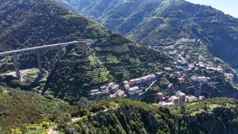 drone footage of a small village on the coast of cinque terre with mountains in italy.