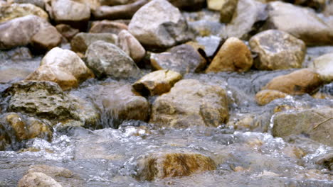 Clear-stream-running-through-stone-boulders-Abundant-river-flowing-in-slow-motion