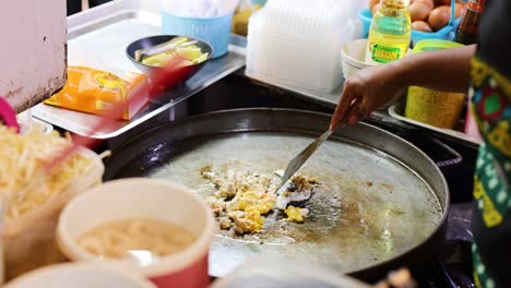 preparing an egg omelet on a street food stall