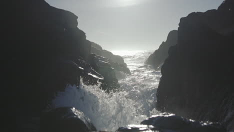 slow motion low angle close up shot of an ocean waves splashing on rocks close to camera